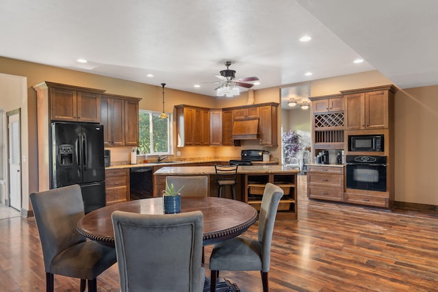 kitchen featuring sink, a kitchen island, decorative light fixtures, black appliances, and dark hardwood / wood-style floors