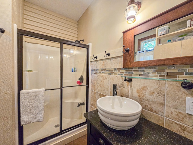 bathroom featuring a shower with door, vanity, and tile walls