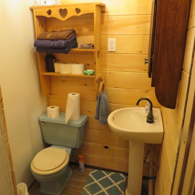 bathroom featuring sink, wooden walls, and toilet