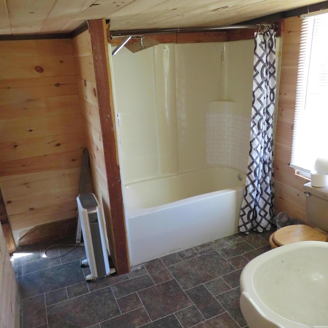 bathroom with tile patterned flooring, shower / bathtub combination with curtain, wooden walls, and toilet