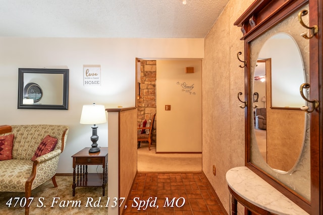 hallway with dark carpet and a textured ceiling