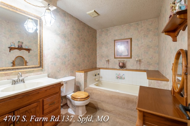 bathroom featuring a textured ceiling, a relaxing tiled tub, toilet, and vanity