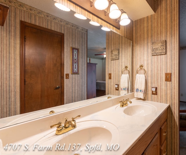 bathroom featuring ceiling fan, vanity, and a textured ceiling