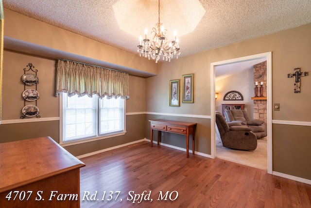 interior space with a textured ceiling, a chandelier, and hardwood / wood-style floors