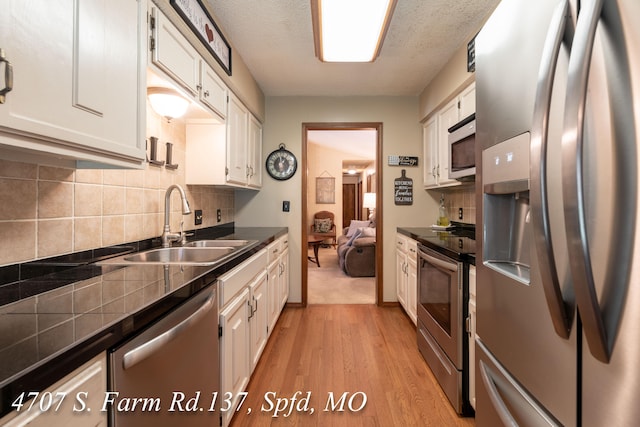 kitchen with light hardwood / wood-style flooring, appliances with stainless steel finishes, sink, and white cabinetry