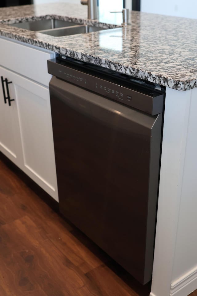 kitchen with sink, white cabinetry, dishwasher, light stone countertops, and dark hardwood / wood-style flooring