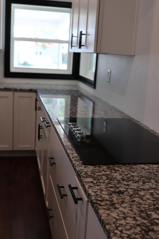 kitchen with black electric cooktop, white cabinets, dark hardwood / wood-style floors, and stone counters