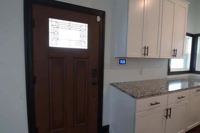 interior space with light stone counters and white cabinetry