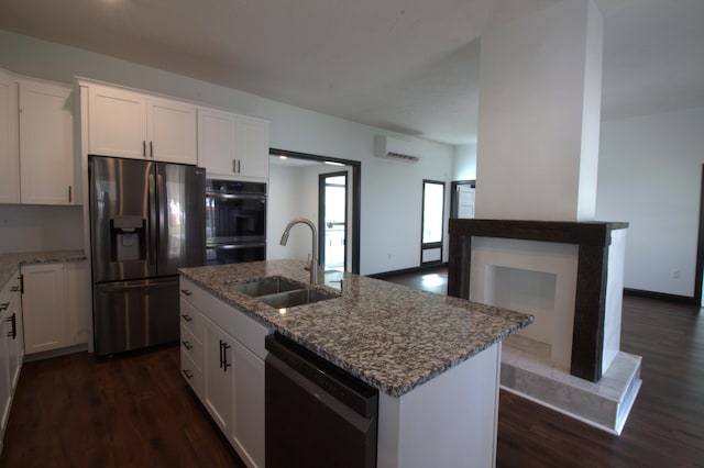 kitchen with an island with sink, black appliances, sink, and white cabinetry