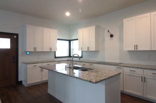 kitchen with white cabinets, dark wood-type flooring, sink, a center island with sink, and black electric stovetop