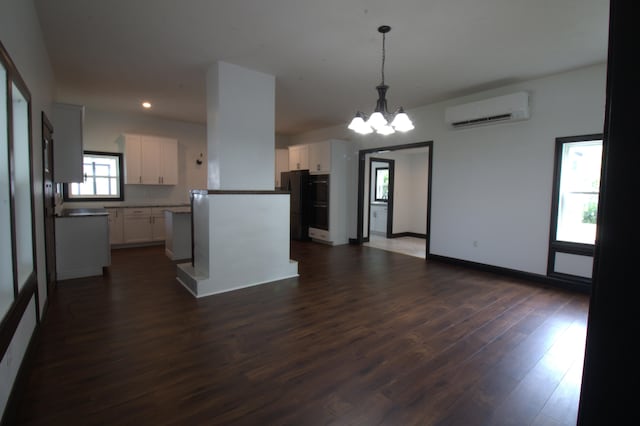 327 E Chestnut St, Bolivar, MO 65613 - kitchen with white cabinets, an AC wall unit, dark wood-style flooring, freestanding refrigerator, and a notable chandelier