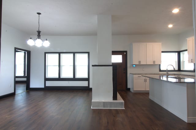 kitchen featuring white cabinets, dark wood-type flooring, sink, hanging light fixtures, and stone countertops