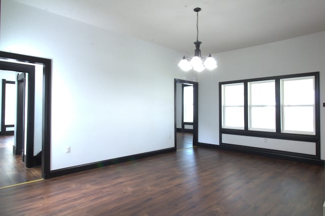 spare room with an inviting chandelier and dark hardwood / wood-style flooring