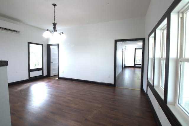 unfurnished room with a chandelier, a wall mounted AC, and dark hardwood / wood-style flooring