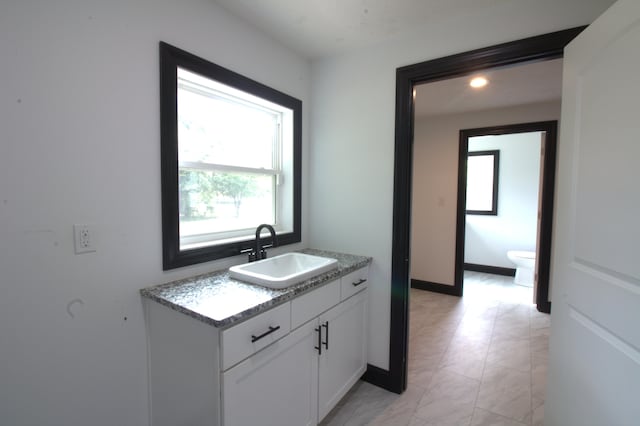 bathroom featuring a healthy amount of sunlight, vanity, and toilet