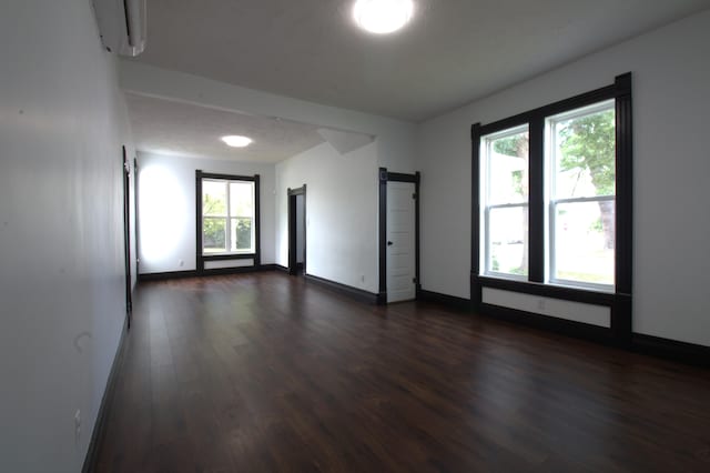327 E Chestnut St, Bolivar, MO 65613 - spare room featuring baseboards, an AC wall unit, a barn door, and dark wood finished floors