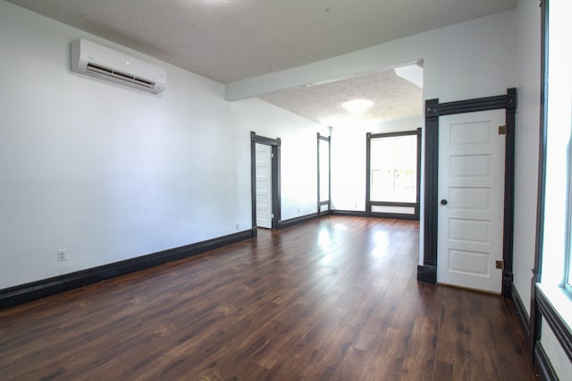 empty room featuring a textured ceiling, dark hardwood / wood-style floors, and a wall mounted air conditioner