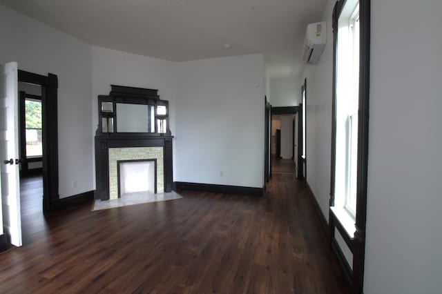 327 E Chestnut St, Bolivar, MO 65613 - unfurnished living room with dark wood finished floors, a wall mounted AC, a stone fireplace, and baseboards