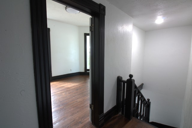 327 E Chestnut St, Bolivar, MO 65613 - corridor with a textured wall, baseboards, dark wood-style flooring, and an upstairs landing