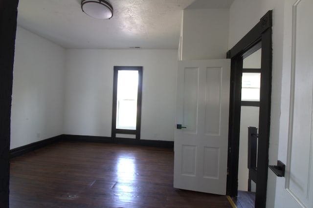 unfurnished room featuring a textured ceiling and dark hardwood / wood-style flooring