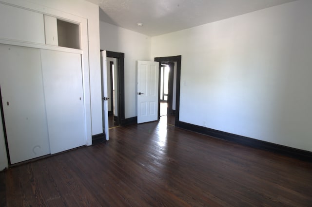 unfurnished bedroom with a closet and dark wood-type flooring