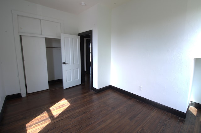 unfurnished bedroom with dark wood-type flooring and a closet