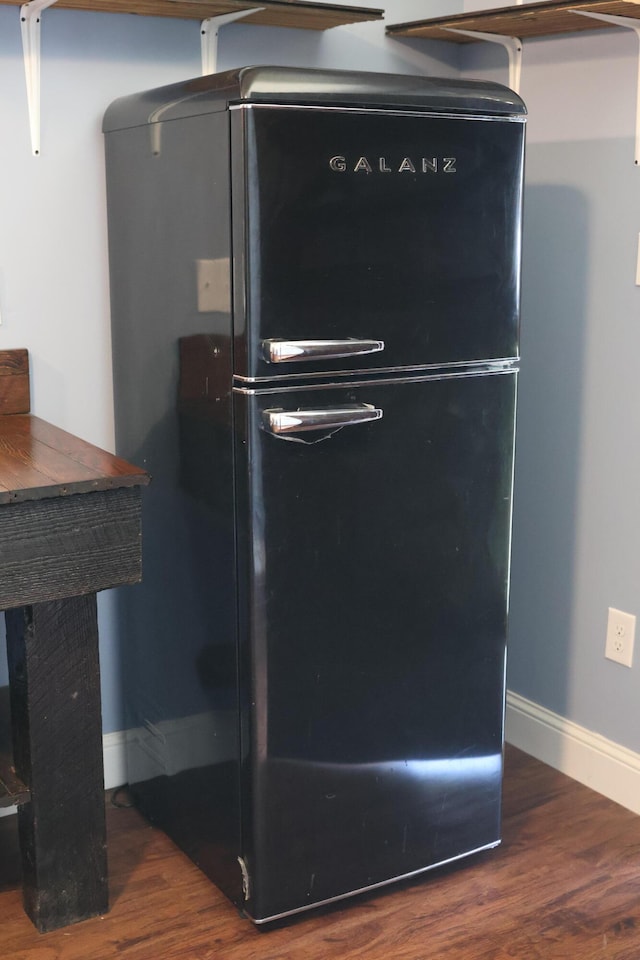 room details with dark hardwood / wood-style flooring and black refrigerator