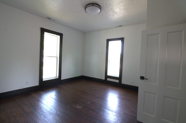 spare room with a textured ceiling and dark hardwood / wood-style floors