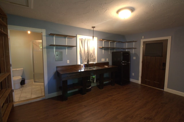 kitchen with dark hardwood / wood-style floors, black fridge, and a textured ceiling