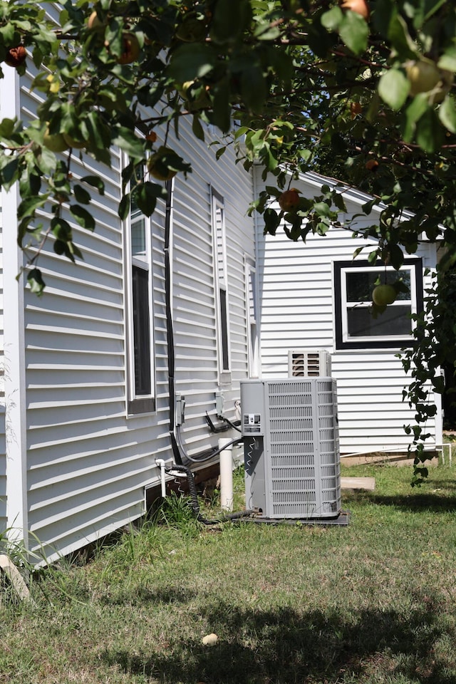 view of home's exterior with a lawn and central AC unit