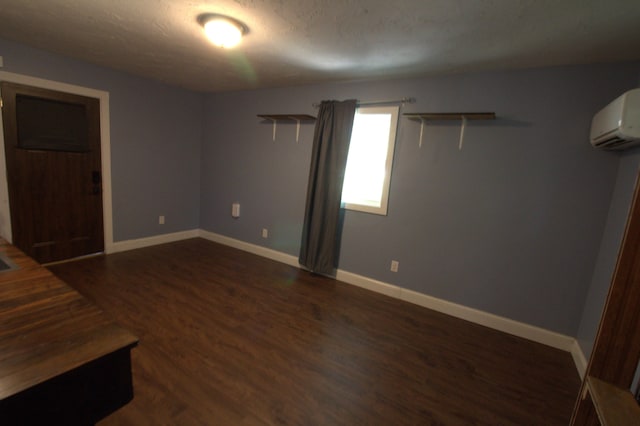 unfurnished room featuring a textured ceiling, a wall mounted air conditioner, and dark hardwood / wood-style flooring