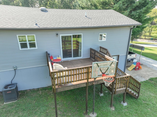 rear view of house with a lawn, a wooden deck, a shingled roof, and central AC