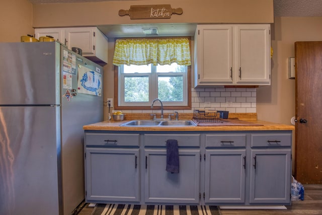 kitchen featuring freestanding refrigerator, decorative backsplash, gray cabinetry, and a sink