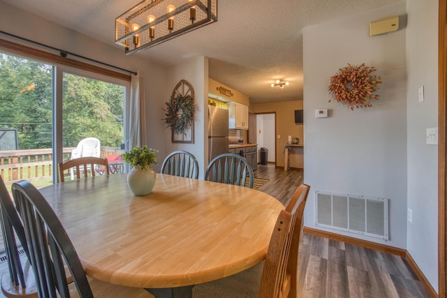 dining space with baseboards, dark wood-style flooring, a textured ceiling, and visible vents