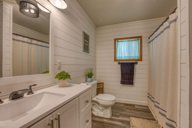 bathroom with wooden walls, wood finished floors, a textured ceiling, and vanity