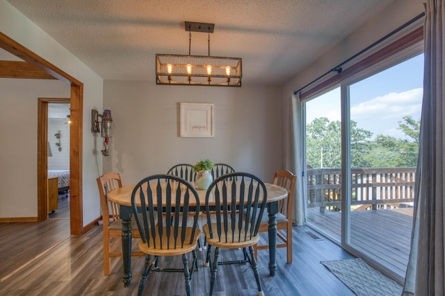 dining room featuring baseboards, visible vents, wood finished floors, and a textured ceiling