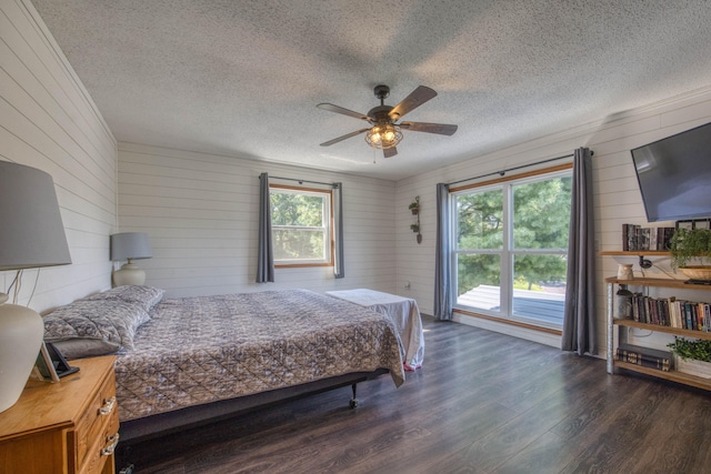 bedroom with ceiling fan, a textured ceiling, dark hardwood / wood-style floors, and multiple windows