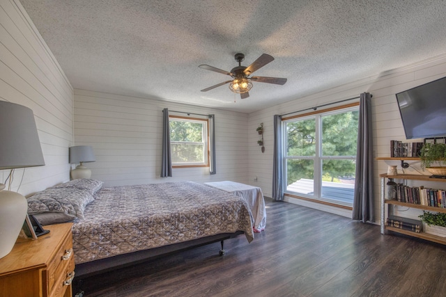 bedroom with wood walls, a ceiling fan, wood finished floors, and a textured ceiling