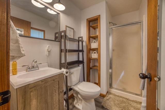 bathroom featuring wood finished floors, vanity, toilet, and a stall shower