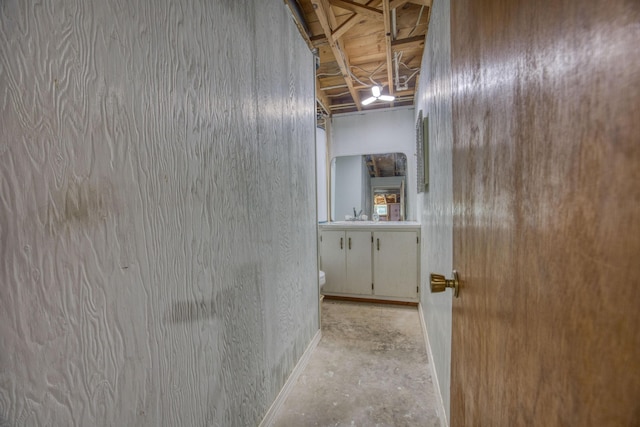 hallway featuring concrete floors, a sink, and baseboards