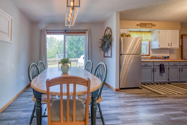 dining room featuring wood finished floors, baseboards, and a textured ceiling