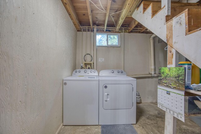 washroom featuring washing machine and dryer, a textured wall, and laundry area