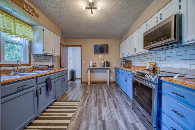 kitchen featuring blue cabinets, stainless steel appliances, a textured ceiling, and a sink