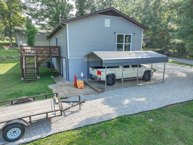 rear view of property with a carport, a lawn, and a deck