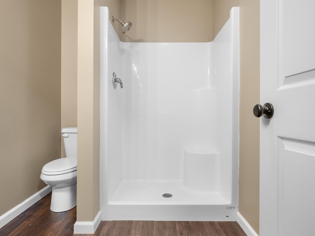 bathroom with wood-type flooring, a shower, and toilet