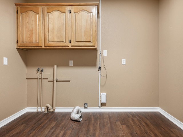 laundry area with dark hardwood / wood-style floors and cabinets