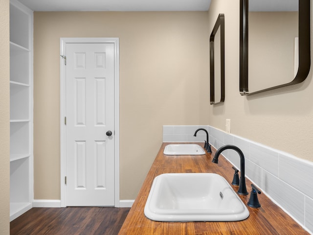 bathroom with dual sinks and hardwood / wood-style floors