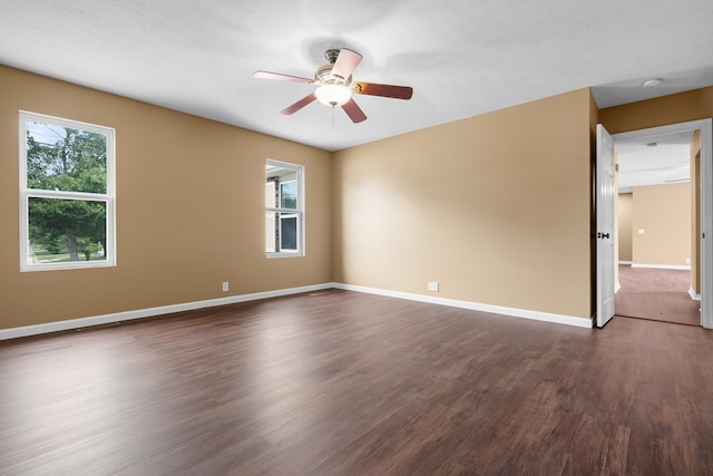 unfurnished room with a textured ceiling, a healthy amount of sunlight, ceiling fan, and dark hardwood / wood-style flooring