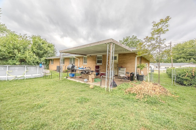 back of property featuring a fenced in pool, a patio area, and a lawn