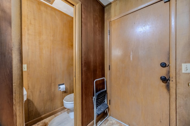 interior space with toilet and wooden walls